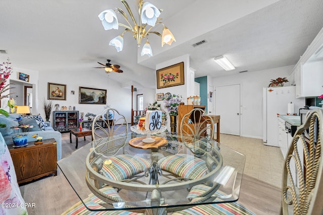 dining room featuring ceiling fan with notable chandelier, light wood-type flooring, lofted ceiling, and a textured ceiling