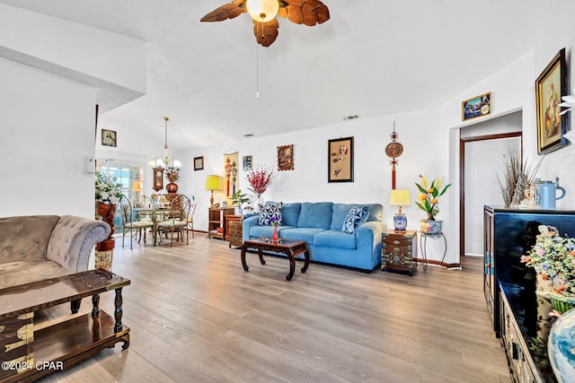 living room with ceiling fan with notable chandelier, lofted ceiling, and light hardwood / wood-style flooring