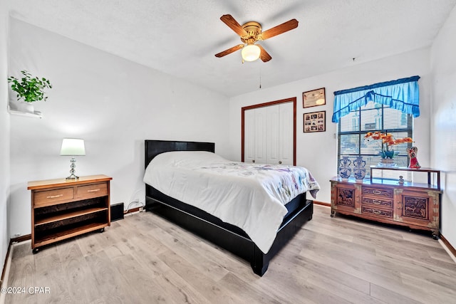 bedroom featuring light hardwood / wood-style flooring, a closet, ceiling fan, and a textured ceiling