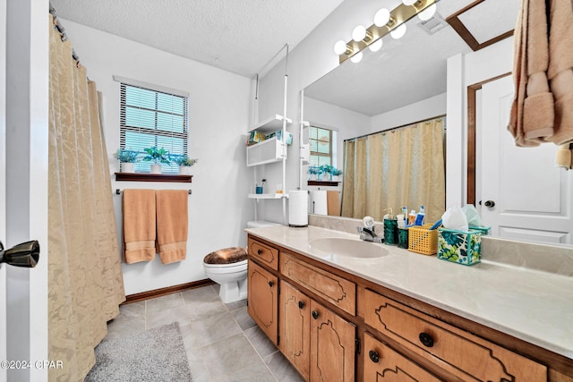 bathroom with tile patterned flooring, a textured ceiling, vanity, and toilet