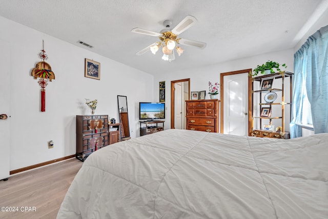 bedroom featuring ceiling fan, a textured ceiling, and light hardwood / wood-style floors