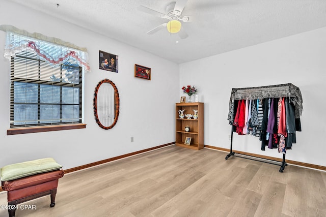 bedroom with light hardwood / wood-style floors, ceiling fan, and a textured ceiling