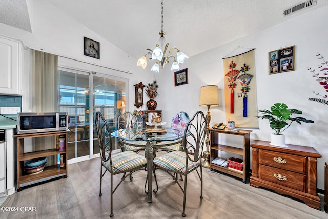 dining space featuring an inviting chandelier, hardwood / wood-style flooring, lofted ceiling, and a textured ceiling