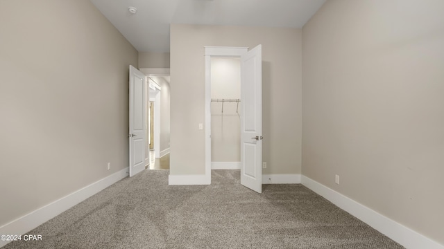 unfurnished bedroom featuring a walk in closet, a closet, and carpet