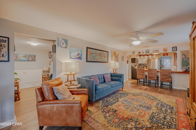 living room with ceiling fan and light hardwood / wood-style flooring