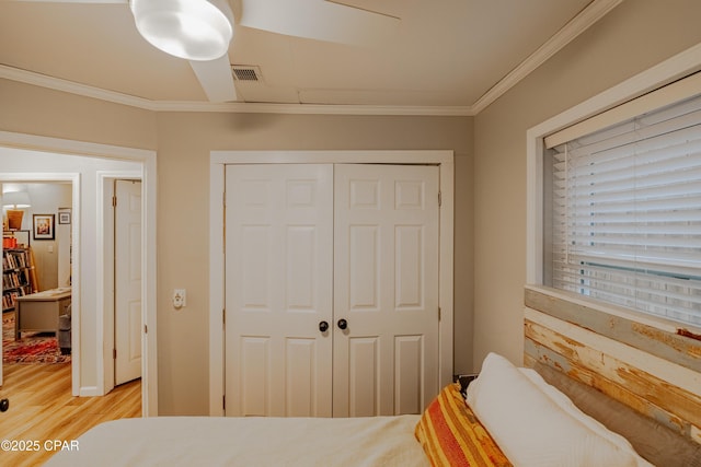 bedroom featuring light wood-type flooring, a closet, and ornamental molding