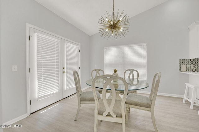 dining space featuring light wood-type flooring, vaulted ceiling, and a notable chandelier