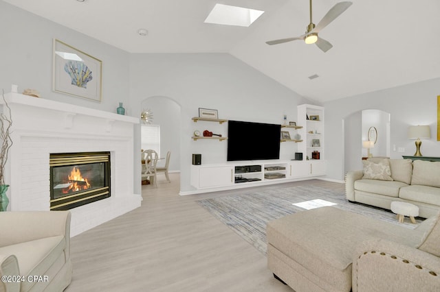 living room featuring hardwood / wood-style floors, vaulted ceiling, a brick fireplace, ceiling fan, and built in features