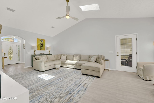 living room with ceiling fan, light hardwood / wood-style flooring, and lofted ceiling with skylight