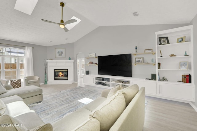 living room with ceiling fan, light wood-type flooring, and lofted ceiling