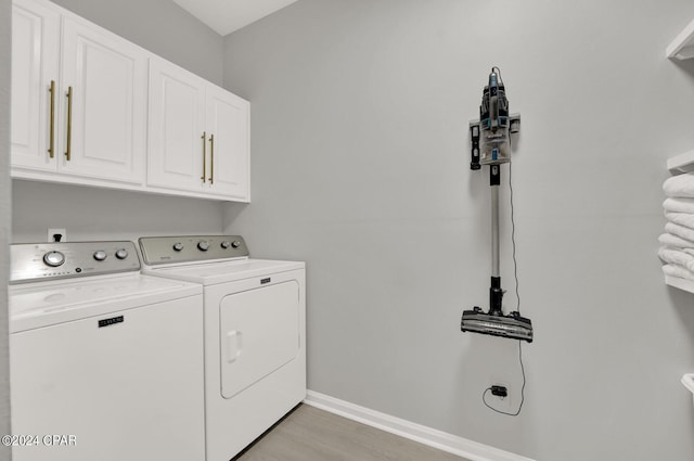 laundry room featuring light hardwood / wood-style floors, cabinets, and washing machine and clothes dryer