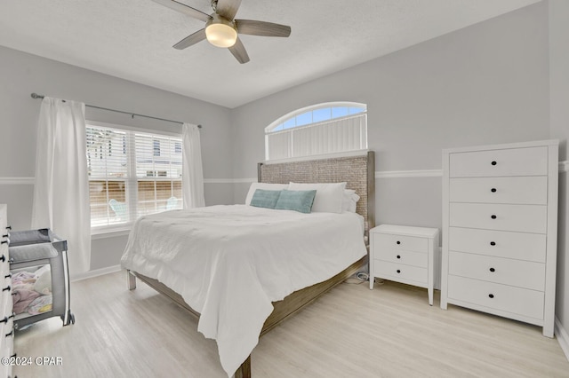 bedroom featuring ceiling fan, light wood-type flooring, and a textured ceiling