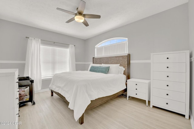 bedroom with ceiling fan, light hardwood / wood-style floors, and a textured ceiling