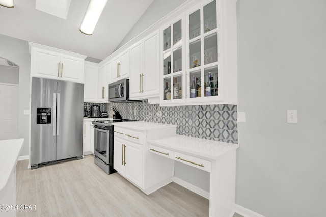 kitchen with white cabinets, lofted ceiling, backsplash, and appliances with stainless steel finishes