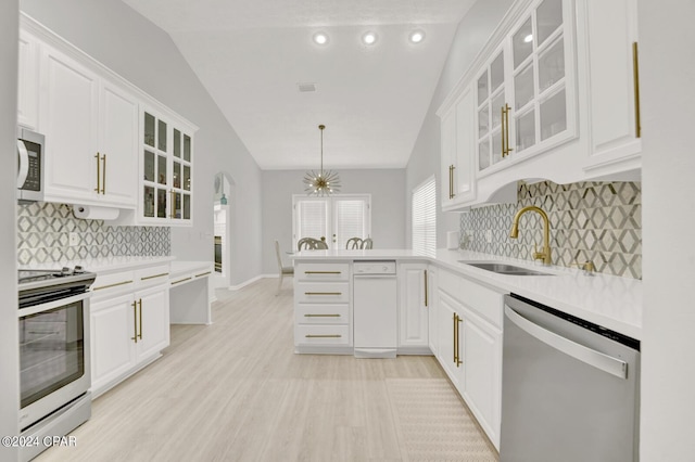 kitchen featuring pendant lighting, sink, vaulted ceiling, kitchen peninsula, and stainless steel appliances