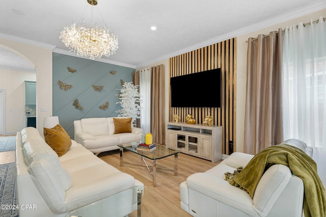 living room with light hardwood / wood-style floors, a textured ceiling, crown molding, and a chandelier