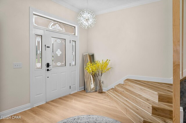 foyer with an inviting chandelier, light hardwood / wood-style floors, and ornamental molding