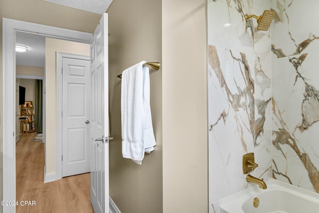 bathroom with tiled shower / bath, a textured ceiling, and wood-type flooring