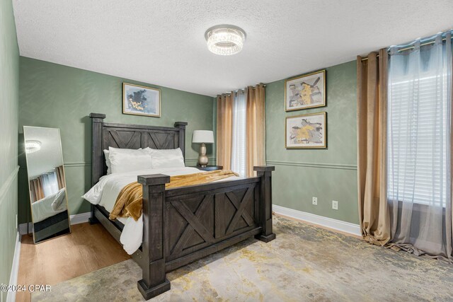 bedroom with multiple windows, a textured ceiling, and light hardwood / wood-style floors