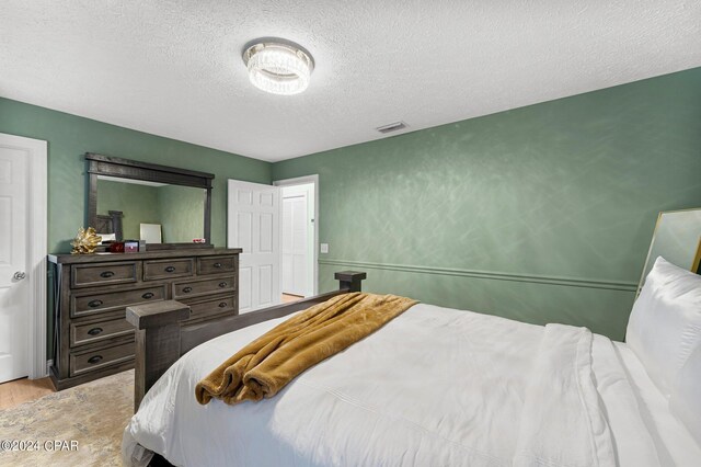 bedroom featuring a textured ceiling and light hardwood / wood-style floors