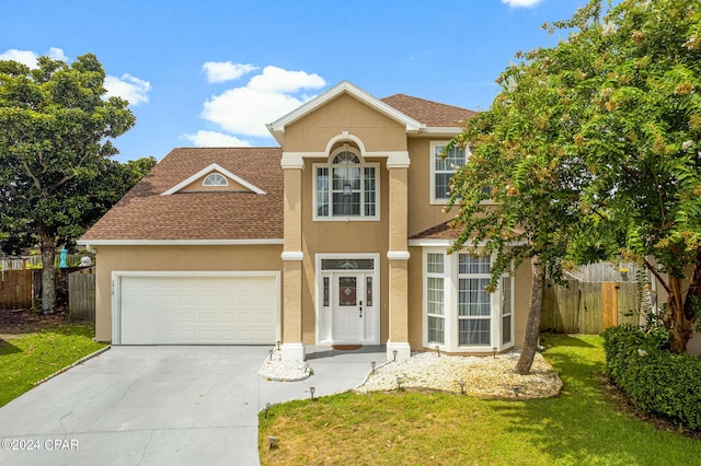 view of property featuring a garage and a front lawn