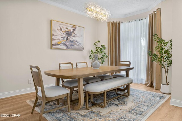 dining room with an inviting chandelier, a textured ceiling, and light hardwood / wood-style flooring