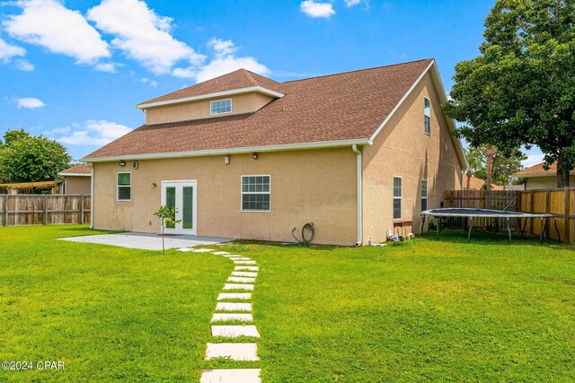 rear view of house featuring a trampoline, a patio, and a yard