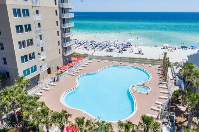 view of swimming pool featuring a water view and a beach view