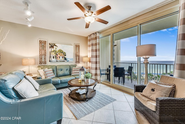 living room featuring light tile patterned floors, ceiling fan, and a water view