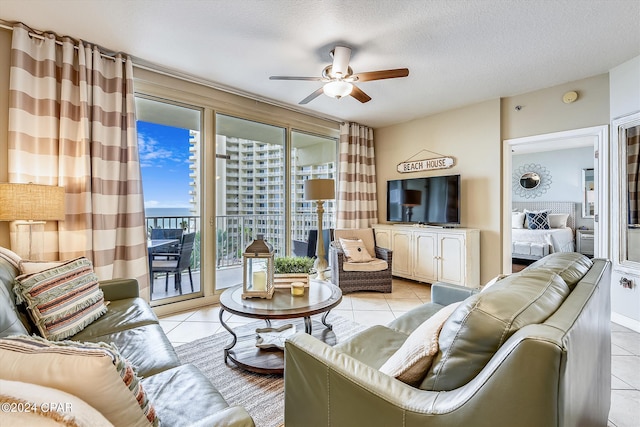 living room with ceiling fan, a textured ceiling, and light tile patterned flooring