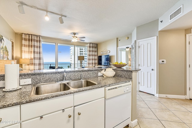 kitchen with sink, white cabinetry, a textured ceiling, light tile patterned floors, and dishwasher