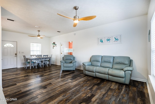 living area with baseboards, wood finished floors, visible vents, and a ceiling fan