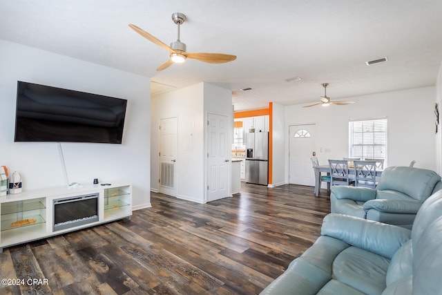 living area with dark wood-style floors, ceiling fan, visible vents, and baseboards