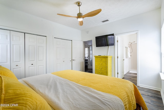 bedroom with multiple closets, visible vents, dark wood-type flooring, a textured ceiling, and baseboards