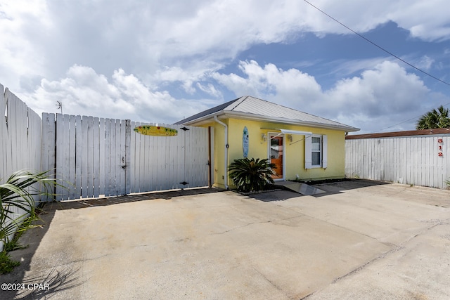 exterior space with metal roof, fence, a gate, and stucco siding