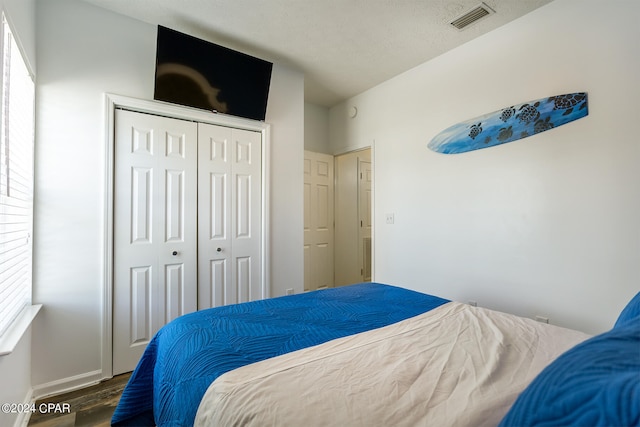 bedroom featuring a closet, visible vents, a textured ceiling, and wood finished floors