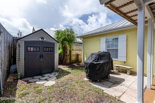 view of yard featuring a storage shed, a fenced backyard, a patio area, and an outbuilding