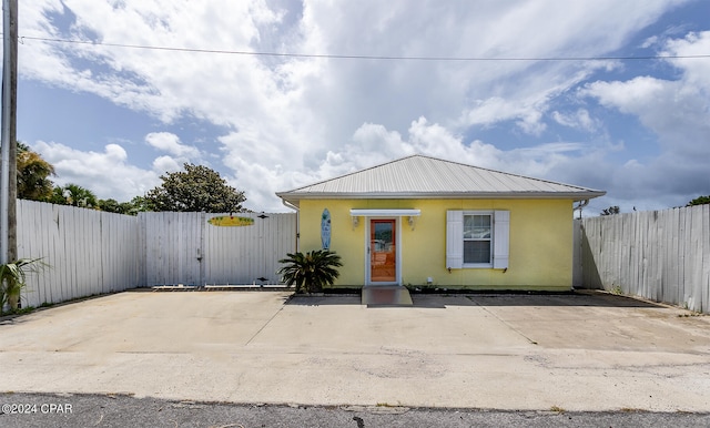 view of front of property featuring metal roof, fence, a gate, and stucco siding