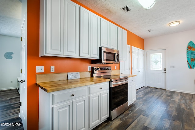 kitchen with dark wood finished floors, stainless steel appliances, visible vents, white cabinets, and wood counters