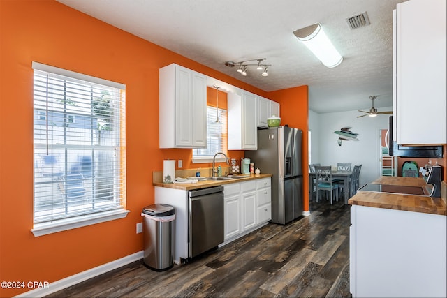 kitchen with white cabinets, dark hardwood / wood-style floors, a healthy amount of sunlight, and stainless steel appliances