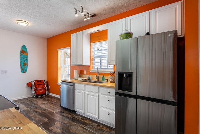 kitchen featuring dark hardwood / wood-style floors, white cabinetry, appliances with stainless steel finishes, sink, and a textured ceiling