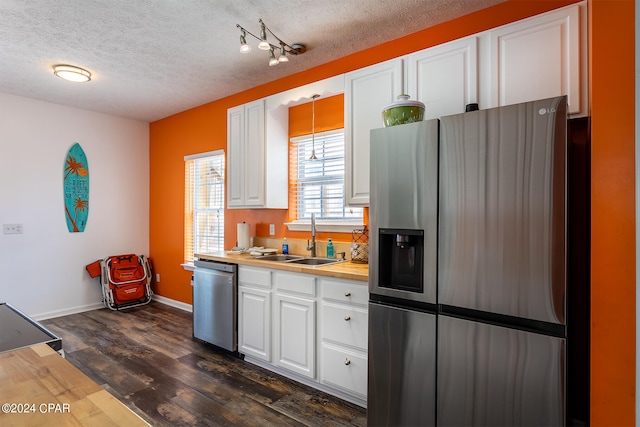 kitchen with dark wood-type flooring, a sink, white cabinets, light countertops, and appliances with stainless steel finishes