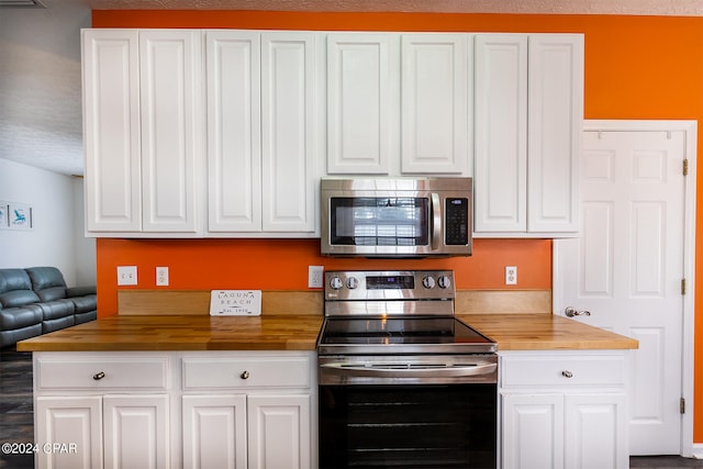 kitchen featuring stainless steel appliances, butcher block counters, and white cabinetry