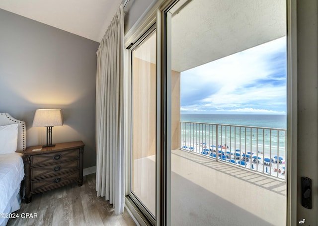 bedroom featuring vaulted ceiling, wood-type flooring, a water view, and a beach view