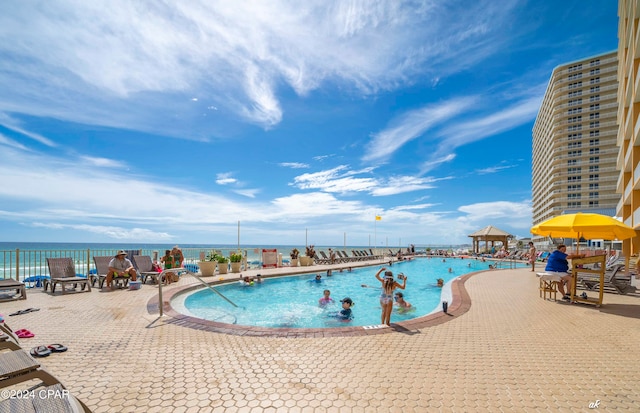 view of pool featuring a gazebo, a water view, and a patio area