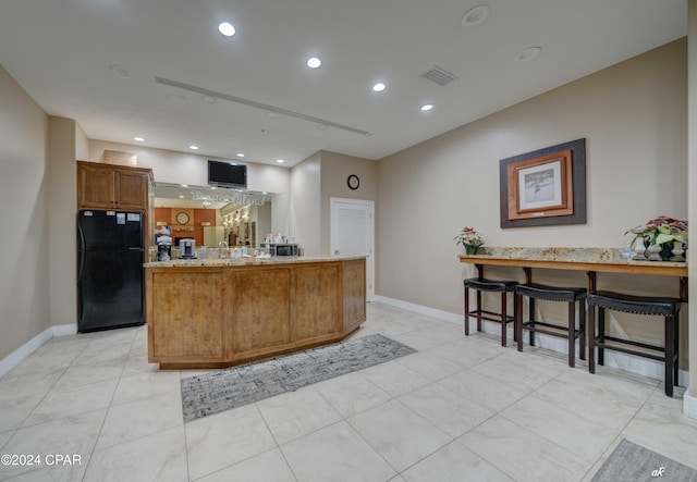 kitchen with black refrigerator, kitchen peninsula, and a kitchen bar