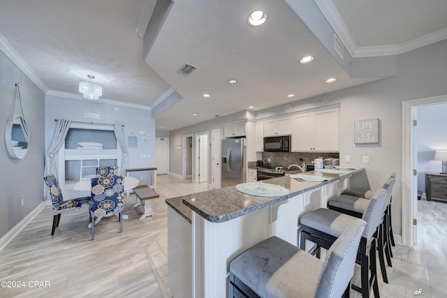 kitchen featuring a breakfast bar, white cabinets, stainless steel fridge, decorative backsplash, and kitchen peninsula