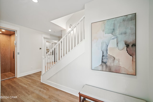 stairway with elevator and wood-type flooring