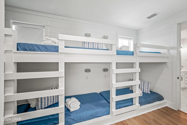 bedroom with hardwood / wood-style floors and wooden walls