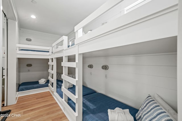 bedroom with wood walls and wood-type flooring